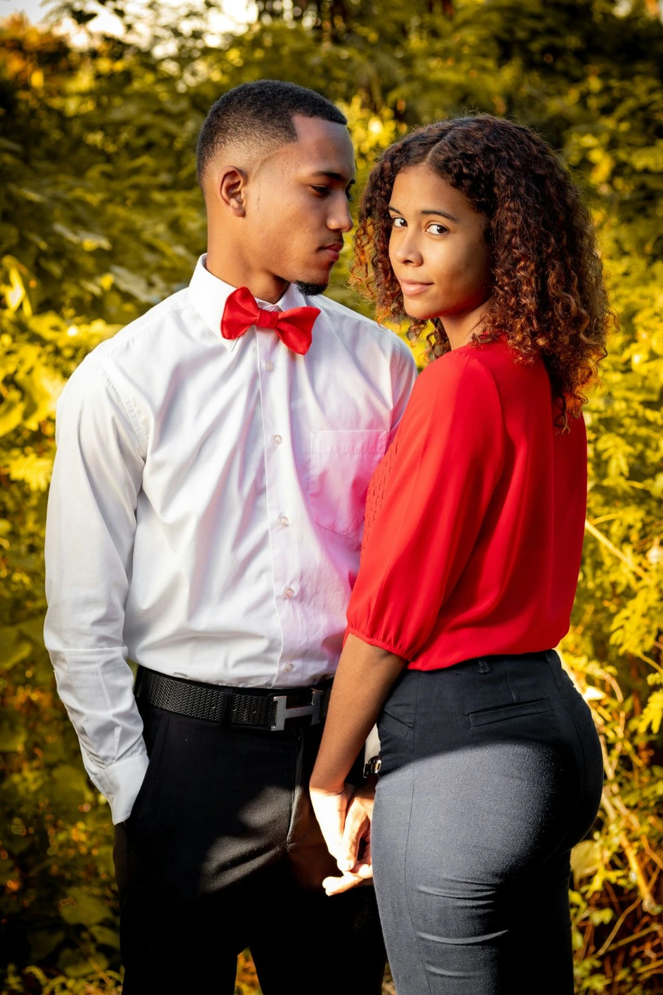 woman in red long sleeve shirt and gray pants standing beside woman in white dress shirt